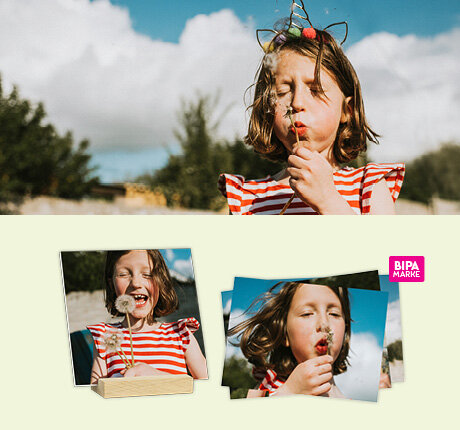 Mädchen bläst Pusteblume im Sonnenschein, links BIPA Fotoshop Abzüge und Fotohalter mit fröhlichem Frühlingsmotiv.
