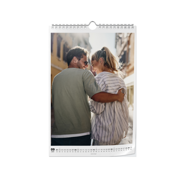 Ein Paar schmiegt sich in einer Stadtumgebung aneinander und lacht, abgebildet auf einem Wandkalender.