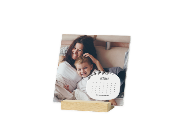 Auf einem Klemmbrettkalender sind Mama und Kind auf einem Sofa zu sehen, die auf etwas schauen und gemeinsam lachen.